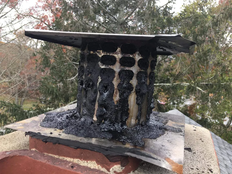 Removed chimney component coated in heavy glazed creosote showing why intact liners matter